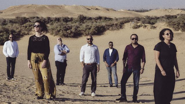 A group of men and women pose together in a desert