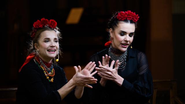 Two women performing on stage, using their hands to express themselves