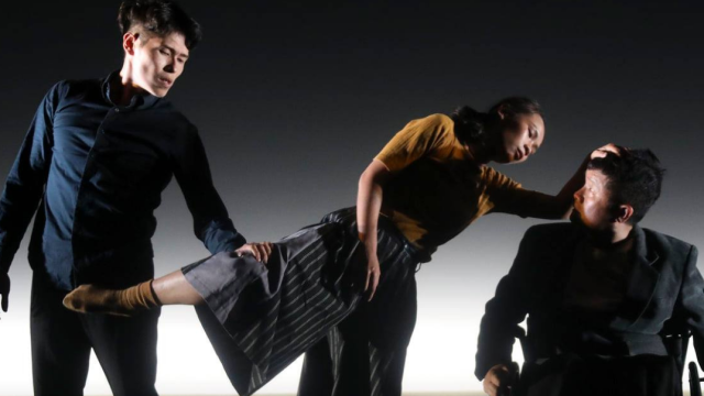Resident Island Dance Theatre by Huang Jyong Jhe A man next to a woman who is standing on one leg and leaning on another man in a wheelchair