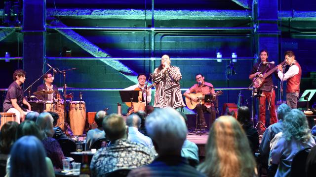 Peruvian band Lundu perform on a stage lit with blue and green lights