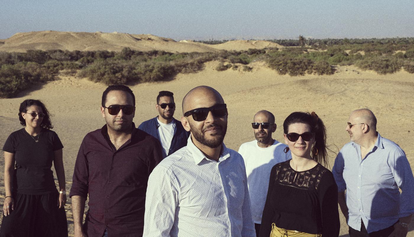 A group of men and women pose together in a desert