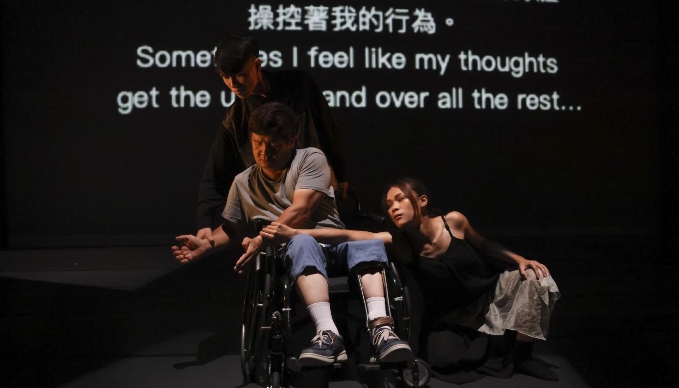 A dancer in a wheelchair is grabbed by the arms by two able-bodied dancers.