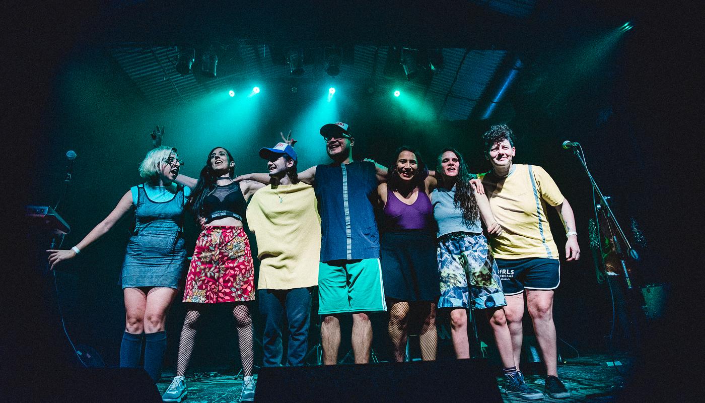 A group of seven musicians taking a bow on stage