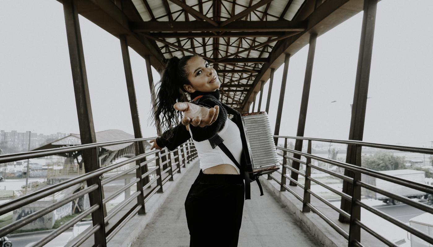 A woman with an accordion standing on a bridge