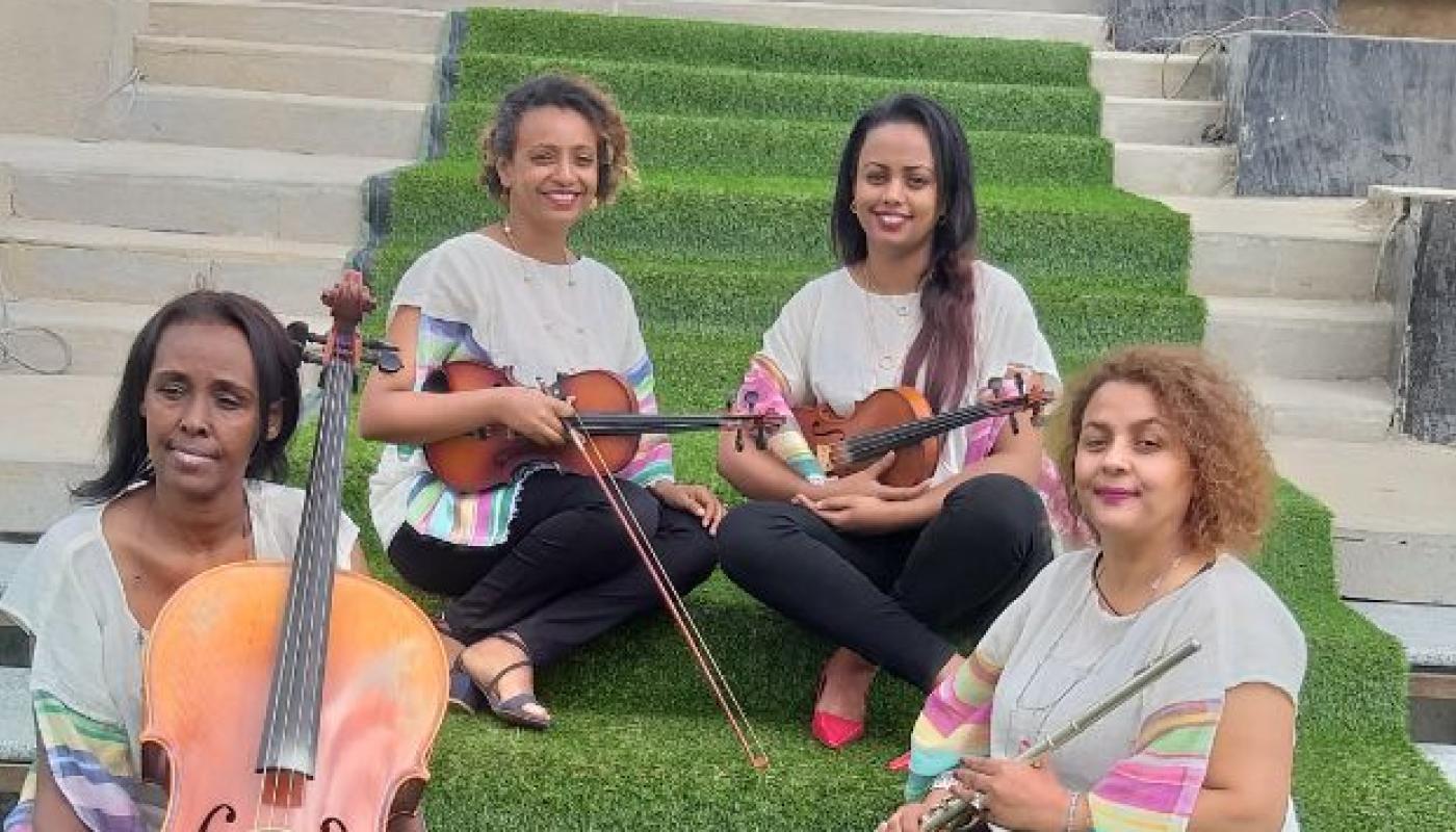 Four women sitting on stairs holding a range of instruments