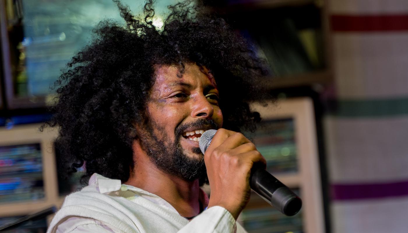 A man holding a microphone, wearing a white shirt