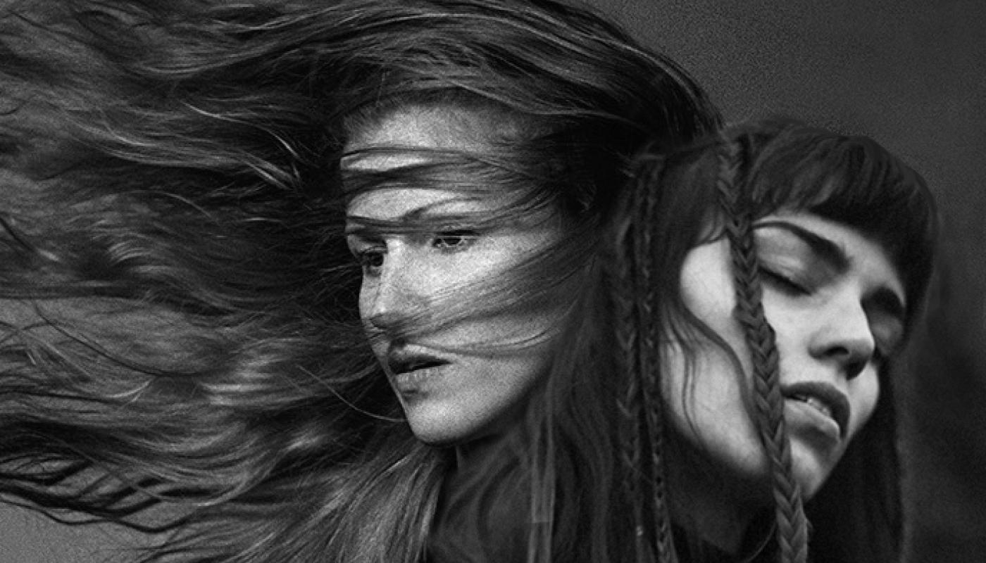 A black and white photo of two women with their hair blowing in the wind