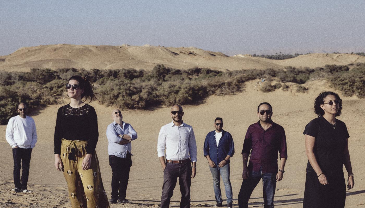 A group of men and women pose together in a desert