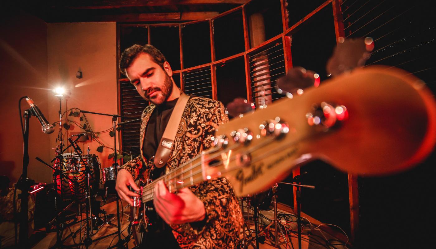 A man holding a guitar with the neck of it in the foreground