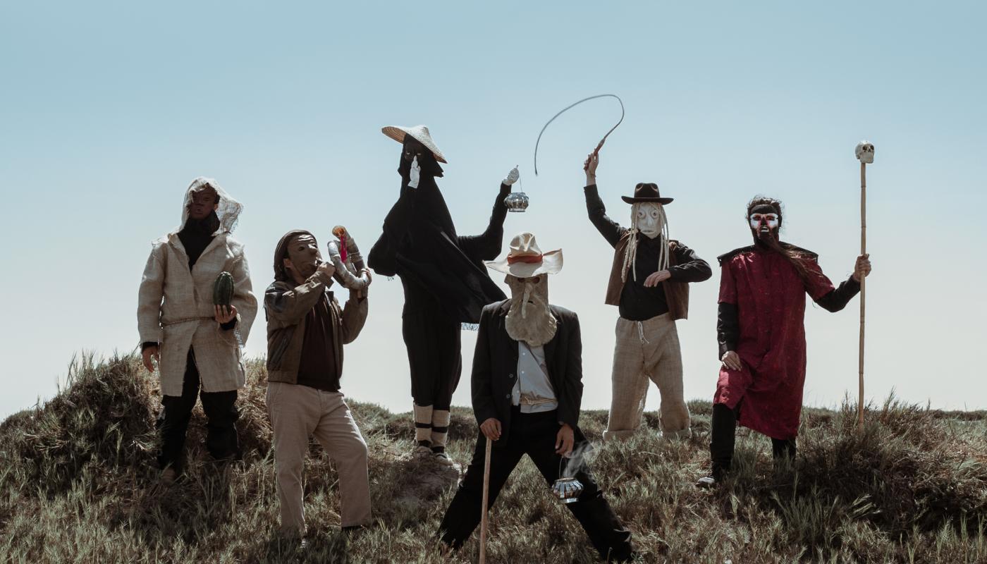 6 people wearing masks on a hill in front of blue sky