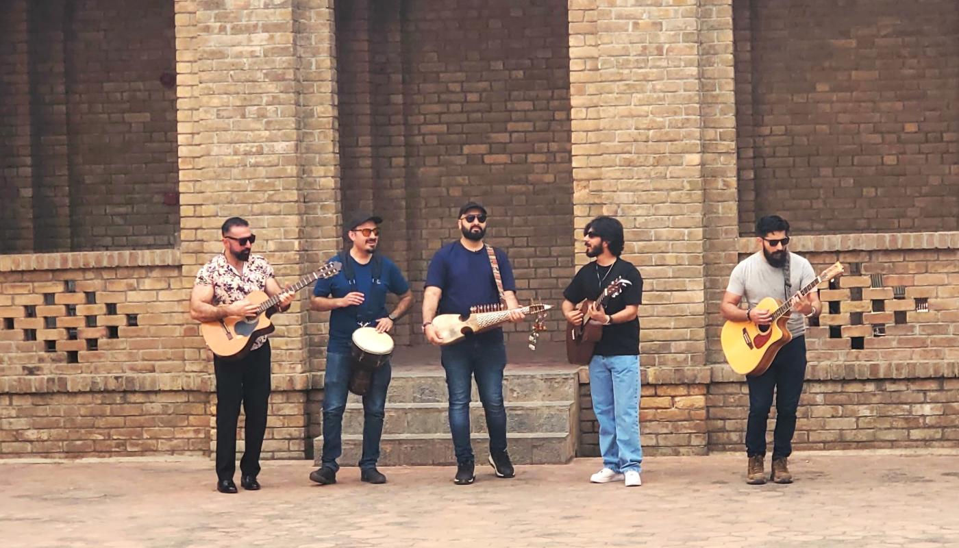 Five musicians with their instruments in a courtyard made of brick