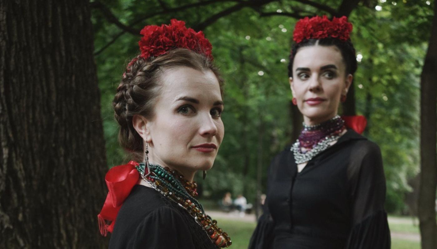 Kurbasy by Daryna Lukjaniuk Two women in traditional Ukranian clothing standing in a forest looking at the camera