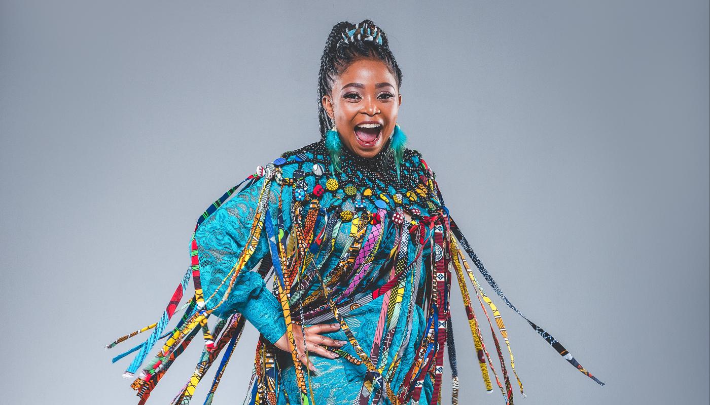 A black woman swings in a circle while posing for the camera wearing brightly colored clothes