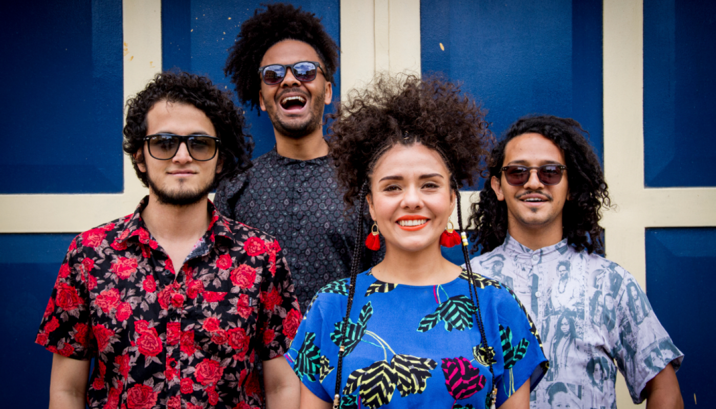 A group of four people standing in front of a blue wall