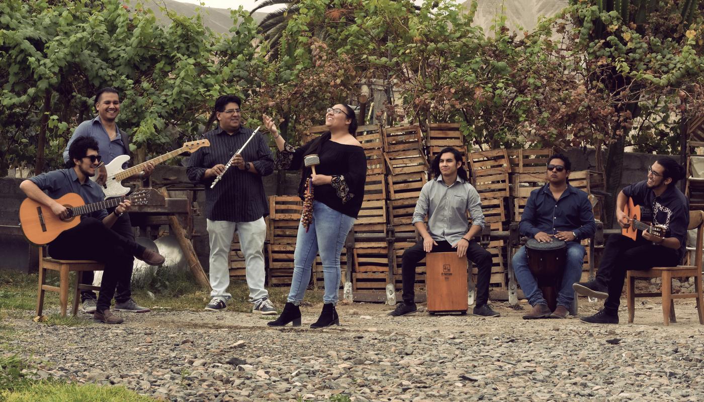 Band playing instruments in front of a brick wall and foliage