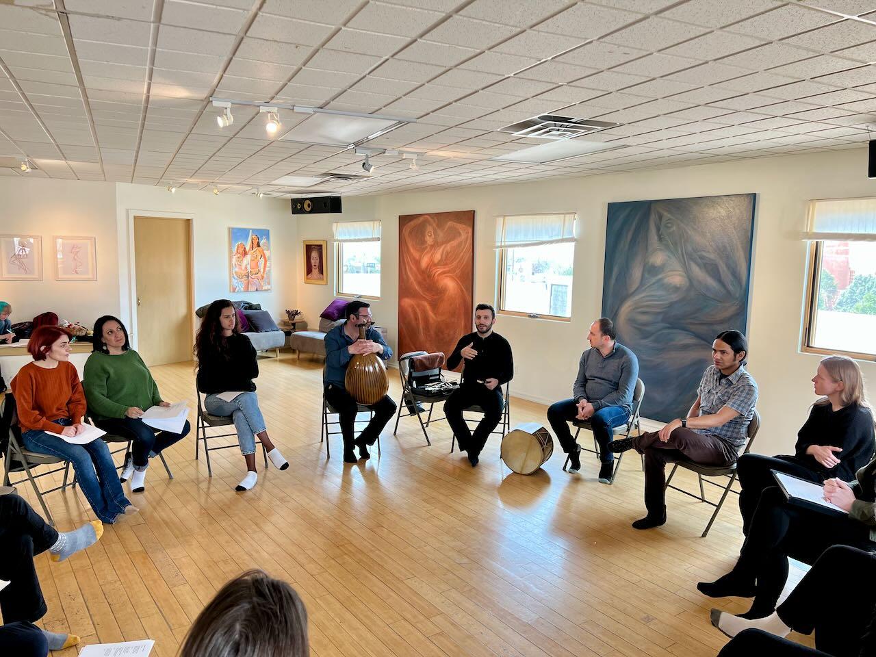 People sitting on chairs, with instruments, in a circle during a workshop