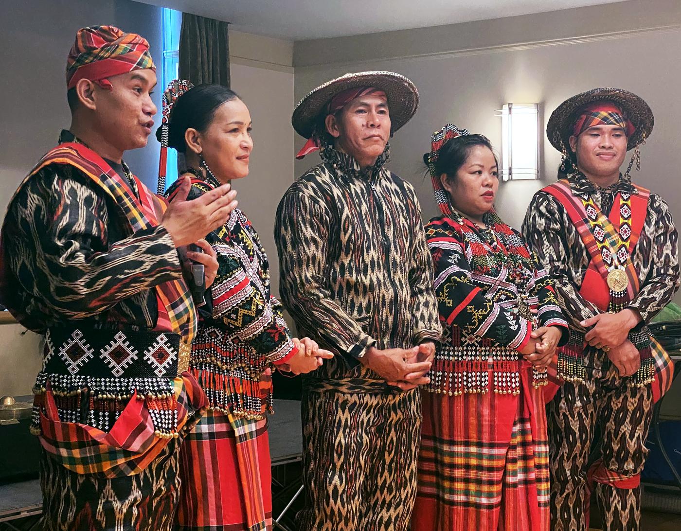 A group of artists stand on a stage in traditional Tboli clothing