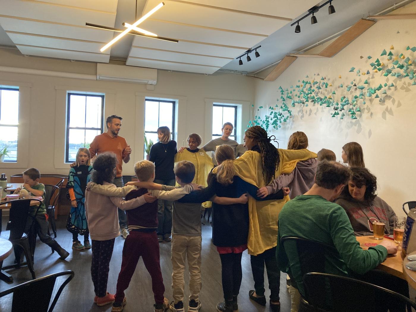 A group of adults and kids play a game together, arms linked