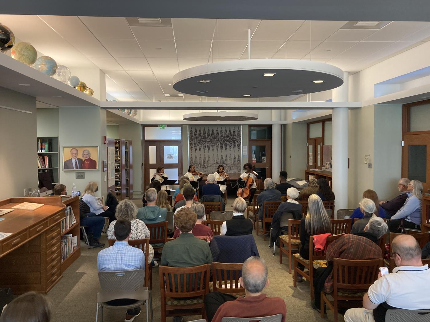 A group of people watch a performance in a library