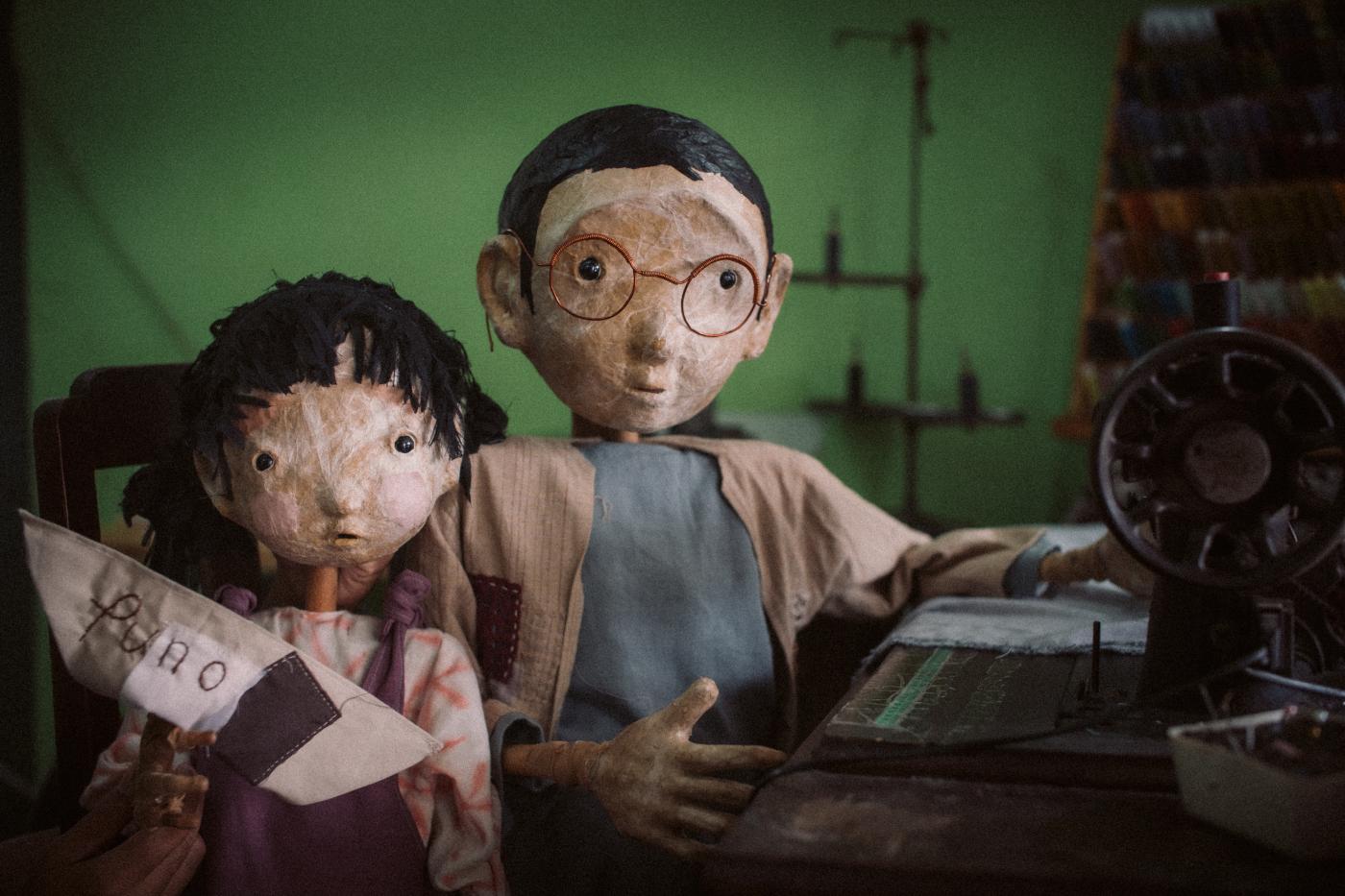Puno, Sewing Memories, photo by Rangga Yudhistir Two puppets looking at the camera, one with a sewing machine and one with a small boat