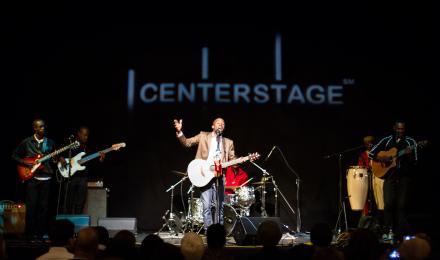 A band performing on a stage, lead singer with their arm out stretched