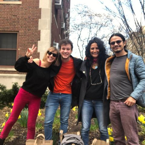 Four people posing in front of a building with daffodils