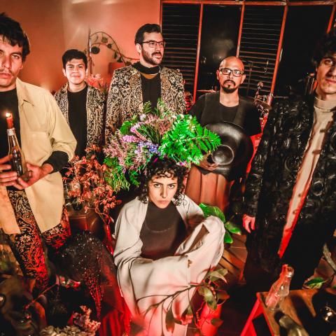 Hit La Rosa by Martiza Mendez Richardson Five men standing with one woman crouched in front, all looking at the camera surrounded by candles