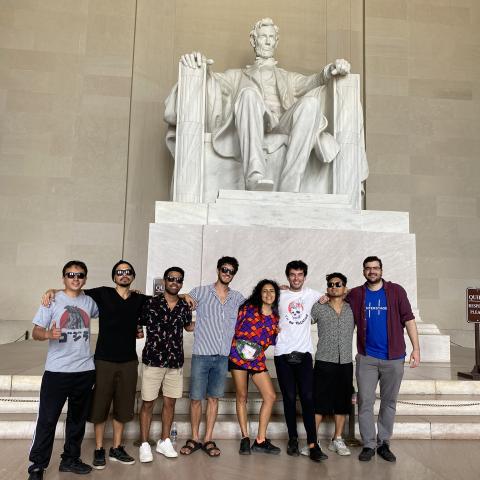 A group of eight adults stand in front of the Lincoln Memorial statue in Washington, DC.
