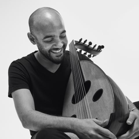Momhamed Abozekry by Khaled Gohar A black and white portrait of a man in a black t-shirt holding an oud.