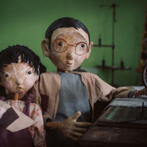 Puno, Sewing Memories, photo by Rangga Yudhistir Two puppets looking at the camera, one with a sewing machine and one with a small boat